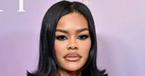 Teyana Taylor poses in a cream military-style outfit inspired by Janet Jackson’s 1993–1995 Janet World Tour, showcasing elegance and nostalgia