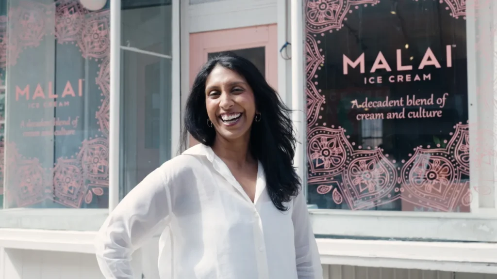 Pooja Bavishi standing inside a Malai shop surrounded by colorful artisanal ice cream tubs inspired by Indian spices.