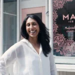 Pooja Bavishi standing inside a Malai shop surrounded by colorful artisanal ice cream tubs inspired by Indian spices.