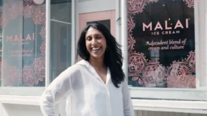 Pooja Bavishi standing inside a Malai shop surrounded by colorful artisanal ice cream tubs inspired by Indian spices.