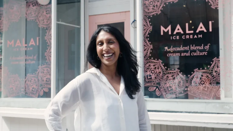 Pooja Bavishi standing inside a Malai shop surrounded by colorful artisanal ice cream tubs inspired by Indian spices.